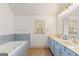 Bathroom featuring double sinks and a jacuzzi tub with light blue accent tile at 1202 Persimmon Way, Mcdonough, GA 30252