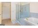 Modern bathroom boasting a glass shower, jacuzzi tub, and blue accent tile at 1202 Persimmon Way, Mcdonough, GA 30252