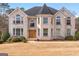 Elegant brick home featuring a turret, arched windows, manicured bushes and a well-maintained lawn at 1202 Persimmon Way, Mcdonough, GA 30252