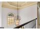 Hallway featuring a unique chandelier, wrought-iron railing, and arched window at 1202 Persimmon Way, Mcdonough, GA 30252
