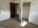 Bedroom featuring neutral carpet, light walls, two open doorways, and a closet with open doors at 2195 Wilson Nw Rd, Conyers, GA 30012