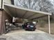 Covered carport with room for parking and storage with a brick home and foliage in the background at 2195 Wilson Nw Rd, Conyers, GA 30012