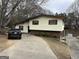 Split-level home with brick foundation, cream siding, brown trim, and a concrete driveway surrounded by trees at 2195 Wilson Nw Rd, Conyers, GA 30012