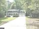 Two-story home with a long driveway and attached two-car garage, surrounded by lush greenery at 305 Glenloch Ln, Stockbridge, GA 30281