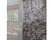 Close-up of a bathtub with a patterned shower curtain and a bright window view at 1704 New Hope Rd, Locust Grove, GA 30248