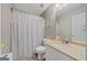 Well-lit bathroom featuring a shower with a patterned curtain, toilet, and a vanity with a mirror at 1704 New Hope Rd, Locust Grove, GA 30248