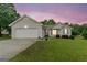 Charming one-story home with vinyl siding, attached garage, and a well-maintained lawn against a sunset sky at 1704 New Hope Rd, Locust Grove, GA 30248