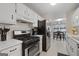 Traditional kitchen featuring white cabinetry, stainless steel appliances, and adjacent dining area with natural light at 1704 New Hope Rd, Locust Grove, GA 30248