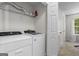 Neat laundry room is complete with modern washer, dryer, shelving and a window with natural light at 11255 Wittenridge Dr, Alpharetta, GA 30022