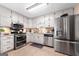Well-lit kitchen featuring stainless steel appliances and plentiful white cabinets at 480 Holly Hills Ln, Mcdonough, GA 30252
