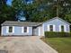 Charming light blue single-story home with white trim, shutters, green bushes, and driveway at 6260 Marbut Farms Ter, Lithonia, GA 30058