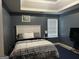Bedroom featuring tray ceiling, dark blue walls, and a comfortable queen-sized bed at 10937 Southwood Dr, Hampton, GA 30228