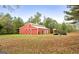A bright red barn with white trim on a beautiful grassy property with a utility trailer at 228 Indian Creek Rd, Locust Grove, GA 30248