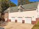 Three car garage with stone accents, a wide driveway, and manicured landscaping, providing ample parking and curb appeal at 228 Indian Creek Rd, Locust Grove, GA 30248