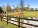 Scenic view of a tranquil pond with a wooden fence, surrounded by lush greenery and a charming home in the distance at 228 Indian Creek Rd, Locust Grove, GA 30248