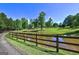 Scenic pond with a wooden fence surrounded by lush greenery and a clear blue sky in a beautiful landscape at 228 Indian Creek Rd, Locust Grove, GA 30248