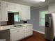 Well-lit kitchen with white cabinets, hardwood floors and stainless steel refrigerator at 1170 5Th Ave, Jonesboro, GA 30236