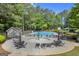 Aerial view of community pool with tables, chairs, umbrellas, shallow water section and slide with trees surrounding at 770 River Cove Dr, Dacula, GA 30019