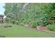 A backyard with a lawn, manicured landscaping, mulch beds, mature trees, and garden pots at 323 Newfield Way, Peachtree City, GA 30269