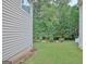 A view of a side yard with a lawn, mulch beds, mature trees, and vinyl siding on the home at 323 Newfield Way, Peachtree City, GA 30269