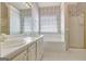 Bathroom boasting a double sink vanity, tiled floors, and a soaking tub with a shower at 323 Newfield Way, Peachtree City, GA 30269