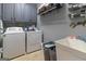 Laundry room with gray cabinets, modern washer and dryer units, and utility sink at 119 Crown Springs Dr, Mcdonough, GA 30252