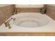 A tiled whirlpool tub with a neutral surroundings, adding elegance and comfort to the bathroom at 411 Hampton Rd, Fayetteville, GA 30215