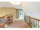 Second floor hallway with wood railing, rocking chair, and neutral carpeting at 411 Hampton Rd, Fayetteville, GA 30215