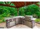 Outdoor kitchen boasts stone countertops, a sink, stainless steel grill, and appliances at 1212 Lee Whatley Dr, Lithonia, GA 30058