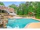 A large, inviting pool features an outdoor kitchen, gazebo, and connected hot tub, surrounded by lush greenery and a serene landscape at 1212 Lee Whatley Dr, Lithonia, GA 30058