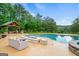 Backyard pool area features a pool, hot tub, outdoor kitchen, fireplace, and seating at 1212 Lee Whatley Dr, Lithonia, GA 30058