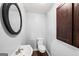 Small powder room featuring a sink, toilet, decorative mirror and a dark wood cabinet for storage at 1212 Lee Whatley Dr, Lithonia, GA 30058