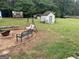 Expansive backyard with a swing, fire pit, and a storage shed in a wooded area at 1125 Babbs Mill Rd, Hampton, GA 30228