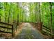Tree-lined driveway leading through a lush forest with rustic wooden and metal gates at 3258 South Mckoy Rd, Villa Rica, GA 30180