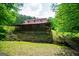 View of a home with a long porch, set against a backdrop of trees, landscaping and a stream at 3258 South Mckoy Rd, Villa Rica, GA 30180
