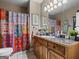Bathroom with a colorful shower curtain, wood vanity, and decorative prints at 124 Belford Way, Locust Grove, GA 30248