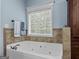 Relaxing bathtub with tiled walls, natural light, and modern fixtures at 124 Belford Way, Locust Grove, GA 30248