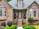 Inviting front porch with brick steps, lovely landscaping, and stone accents at 124 Belford Way, Locust Grove, GA 30248