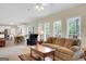Bright living room with a fireplace, windows that let in a lot of light, a ceiling fan, and comfortable furniture at 121 Tamerlane, Peachtree City, GA 30269