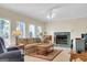 Bright living room with a fireplace, windows that let in a lot of light, a ceiling fan, and comfortable furniture at 121 Tamerlane, Peachtree City, GA 30269