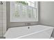 Close up on an elegant soaking tub with white shutters, window, and chrome fixtures at 126 Ardenlee Dr, Peachtree City, GA 30269