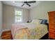 Bright bedroom with hardwood floors, ceiling fan, and colorful floral patterned quilt at 22 Waters Bridge Cir, Covington, GA 30014