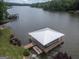 A modern boat dock on the lake with a boat lift, a swim platform, and a green lawn at 22 Waters Bridge Cir, Covington, GA 30014
