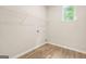 Functional laundry room featuring wood-look flooring, shelving, and a window for natural light at 116 Cabin Way, Hampton, GA 30228