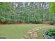 Expansive backyard featuring lush green grass and a charming stone pathway leading through the garden at 120 Hamilton Glen Ct, Fayetteville, GA 30215