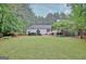 Large backyard with mature trees surrounds a brick and white sided house at 120 Hamilton Glen Ct, Fayetteville, GA 30215