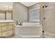 Bright bathroom featuring a soaking tub, glass enclosed shower, and custom cabinetry at 120 Hamilton Glen Ct, Fayetteville, GA 30215