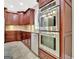 Stainless steel ovens and dishwasher are set within cherry cabinetry in this kitchen at 120 Hamilton Glen Ct, Fayetteville, GA 30215