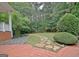 Red brick patio area with stone pathway leading to a green lawn, surrounded by lush landscaping at 120 Hamilton Glen Ct, Fayetteville, GA 30215