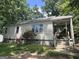 Cozy home with a covered front porch, surrounded by lush greenery and accented by blooming red roses at 530 Whitley Dr, Forest Park, GA 30297